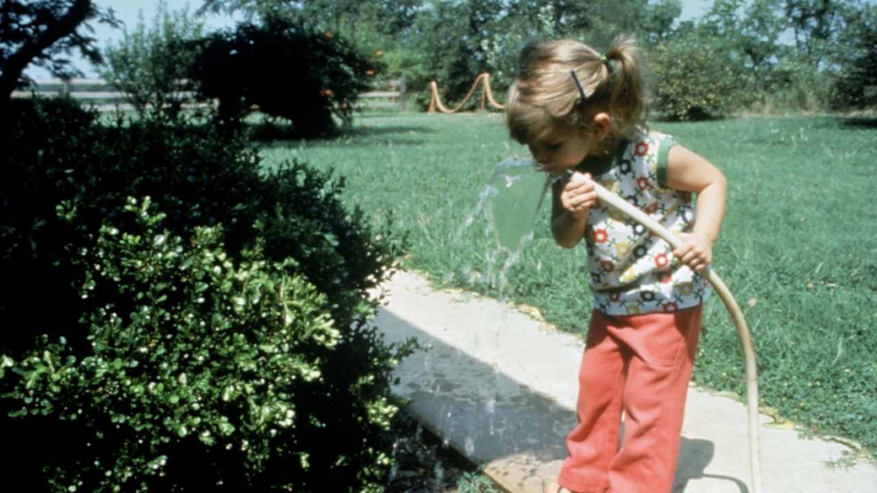 little girl drinking from the hose